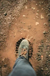 man wearing gray shoe standing on brown soil