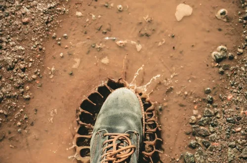man wearing gray shoe standing on brown soil